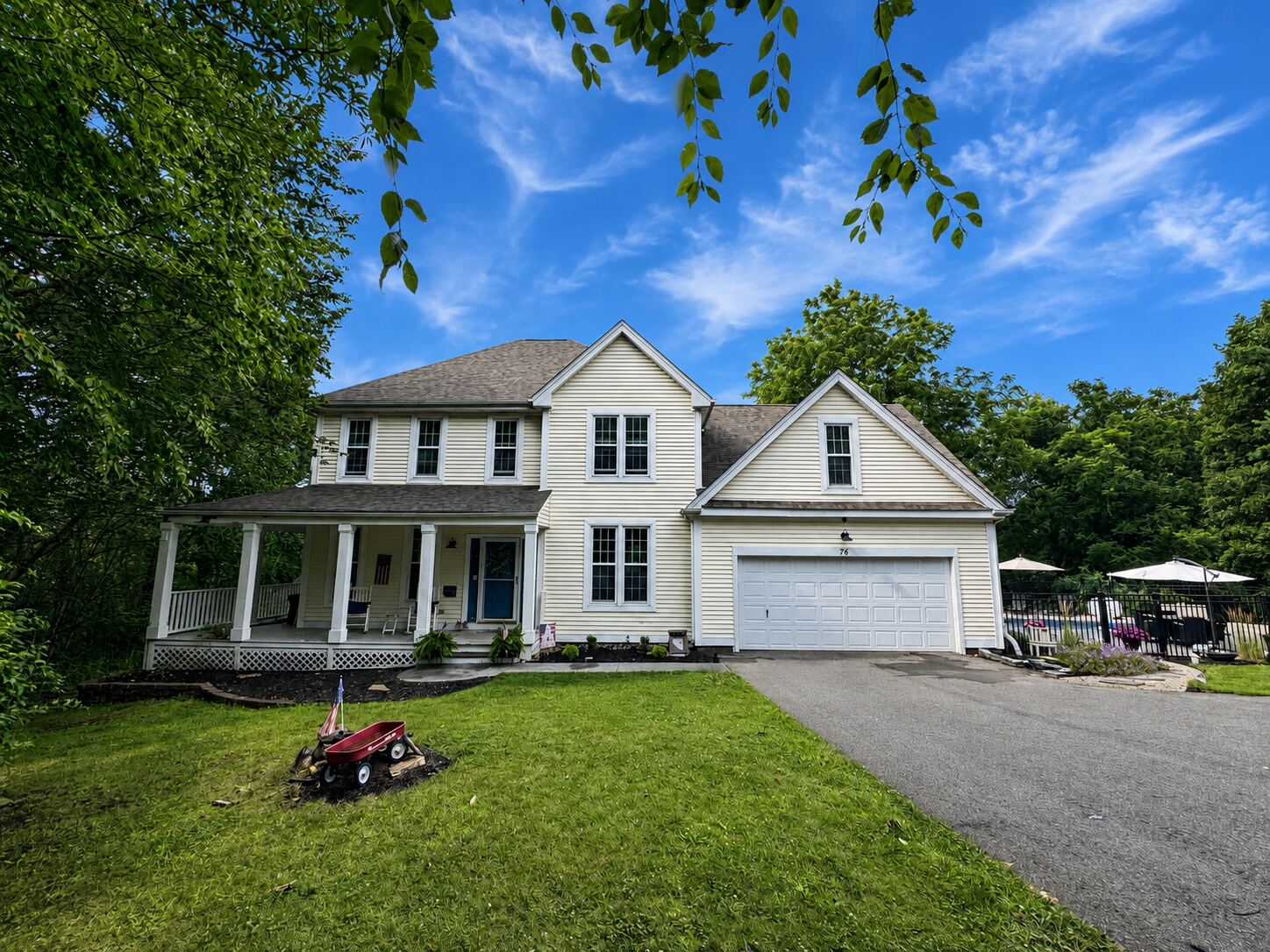 Front exterior of 76R Ivy Way, a cream colonial with a wrap-around covered porch