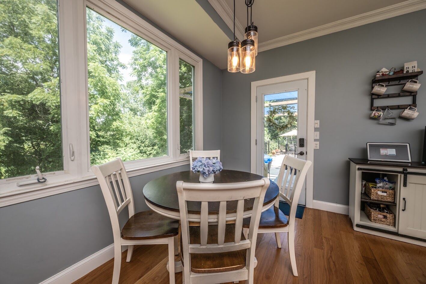 Breakfast nook with corner windows, mason-jar pendant lights, and a door to the deck