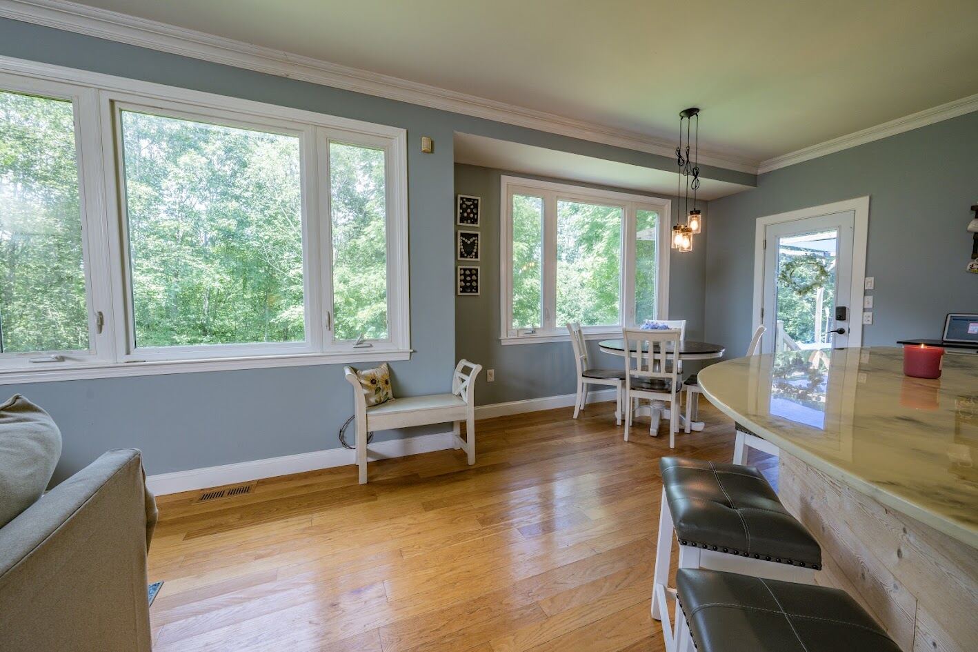 Family room with a wall of custom windows overlooking mature trees and hardwood floors